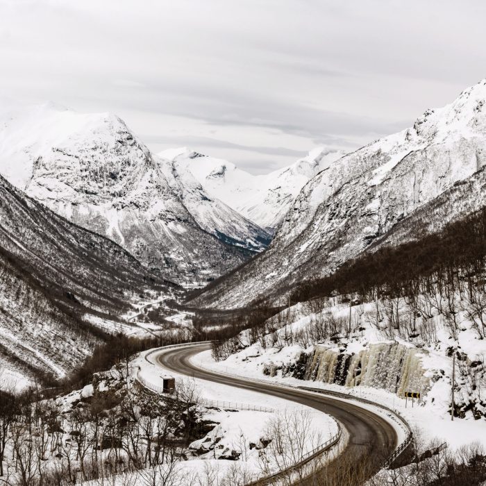A beautiful view of a road surrounded by snow-capped mountains in Norway